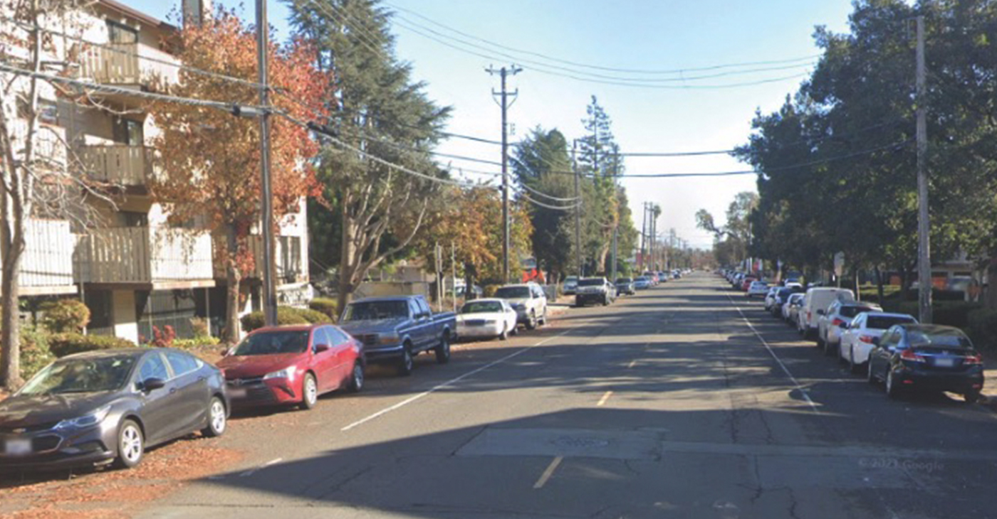 Many cars parked alongside a two-way street in Hayward.