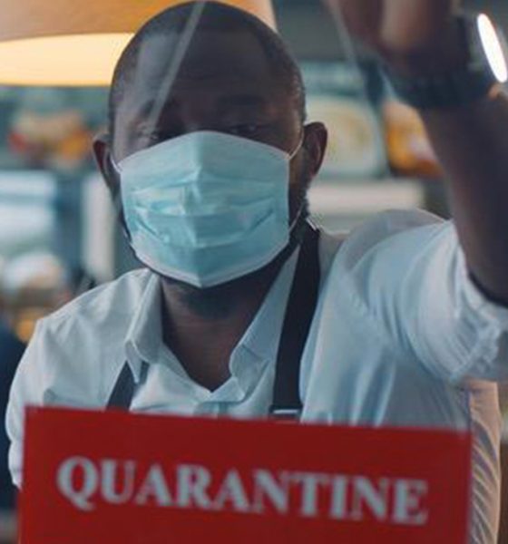 A masked worker stands behind a sign warning of a quarantine. iStock photo.