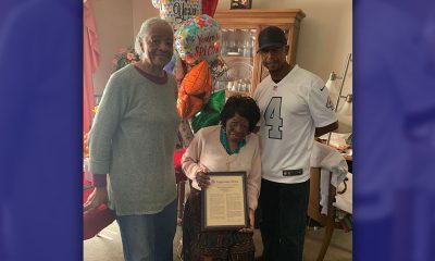 Mrs. Daisy Murray, joined by family members, displays the framed copy of the speech made by U.S. Representative Barbara Lee.