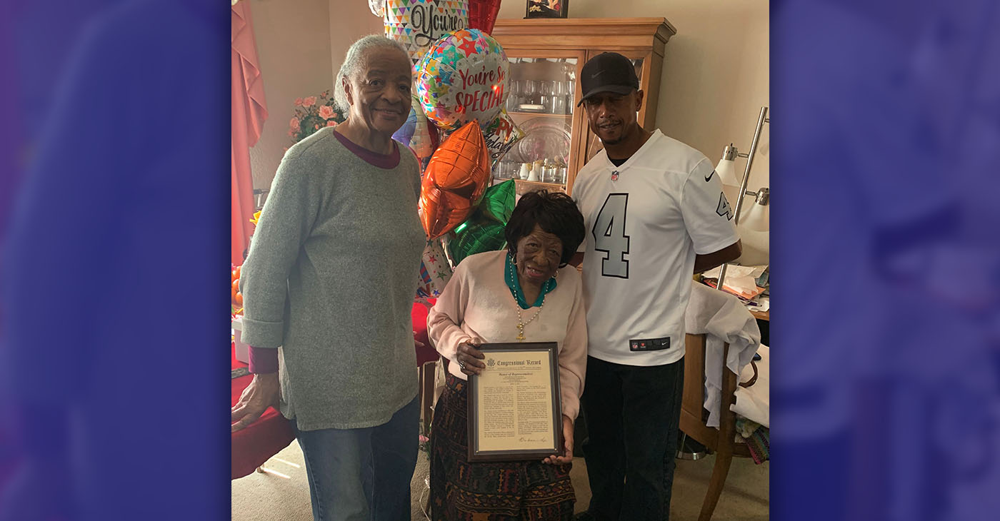 Mrs. Daisy Murray, joined by family members, displays the framed copy of the speech made by U.S. Representative Barbara Lee.