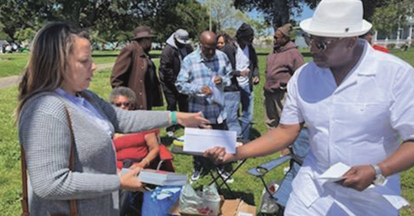 Richard Johnson and some members of the Formerly Incarcerated Giving Back organization give Mother’s Day cash gifts and food. They have distinguished themselves by their efforts to “Just Serve” communities of need and to help rectify the damages they have participated in in the past. Photo by Jonathan Fitness Jones