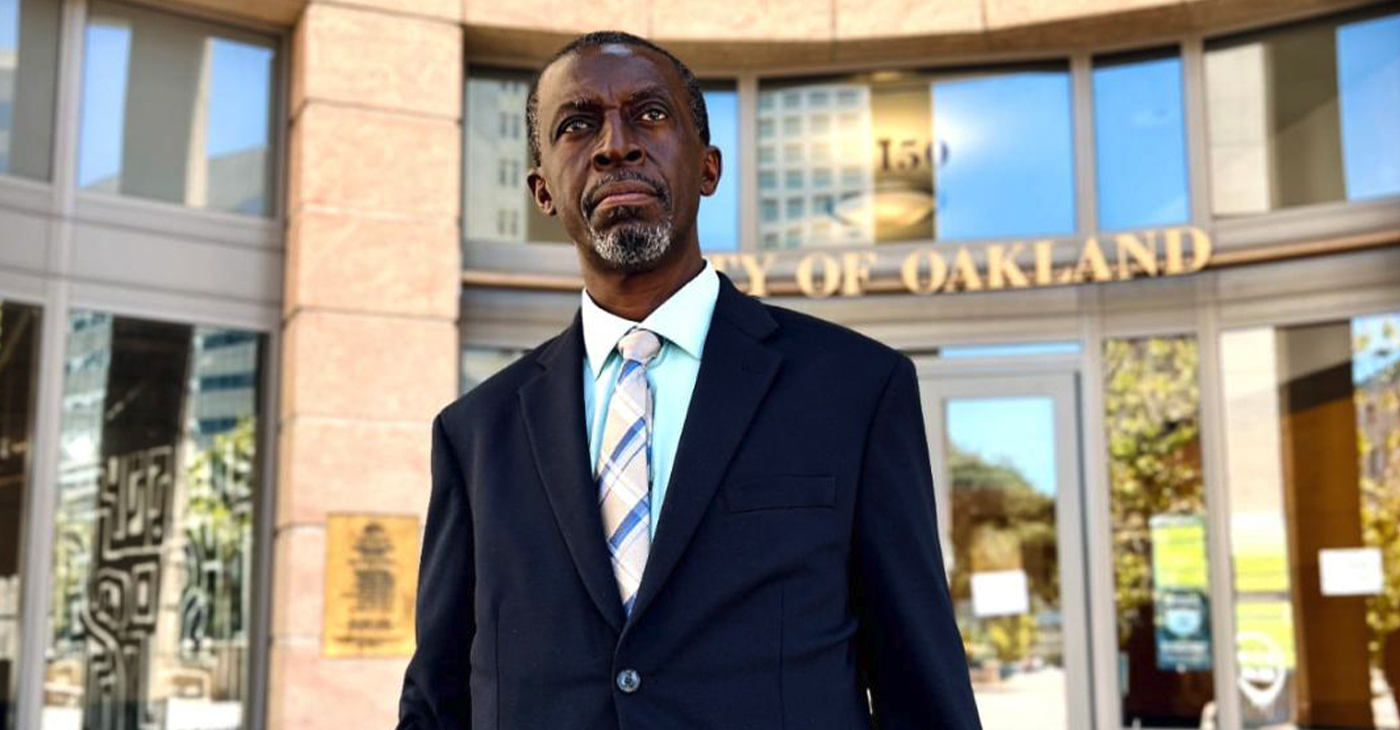 Liberian presidential candidate Tiawan Saye Gongloe at the Federal Building in Oakland holding the broom symbolizing his intent to sweep out corruption in his home country.