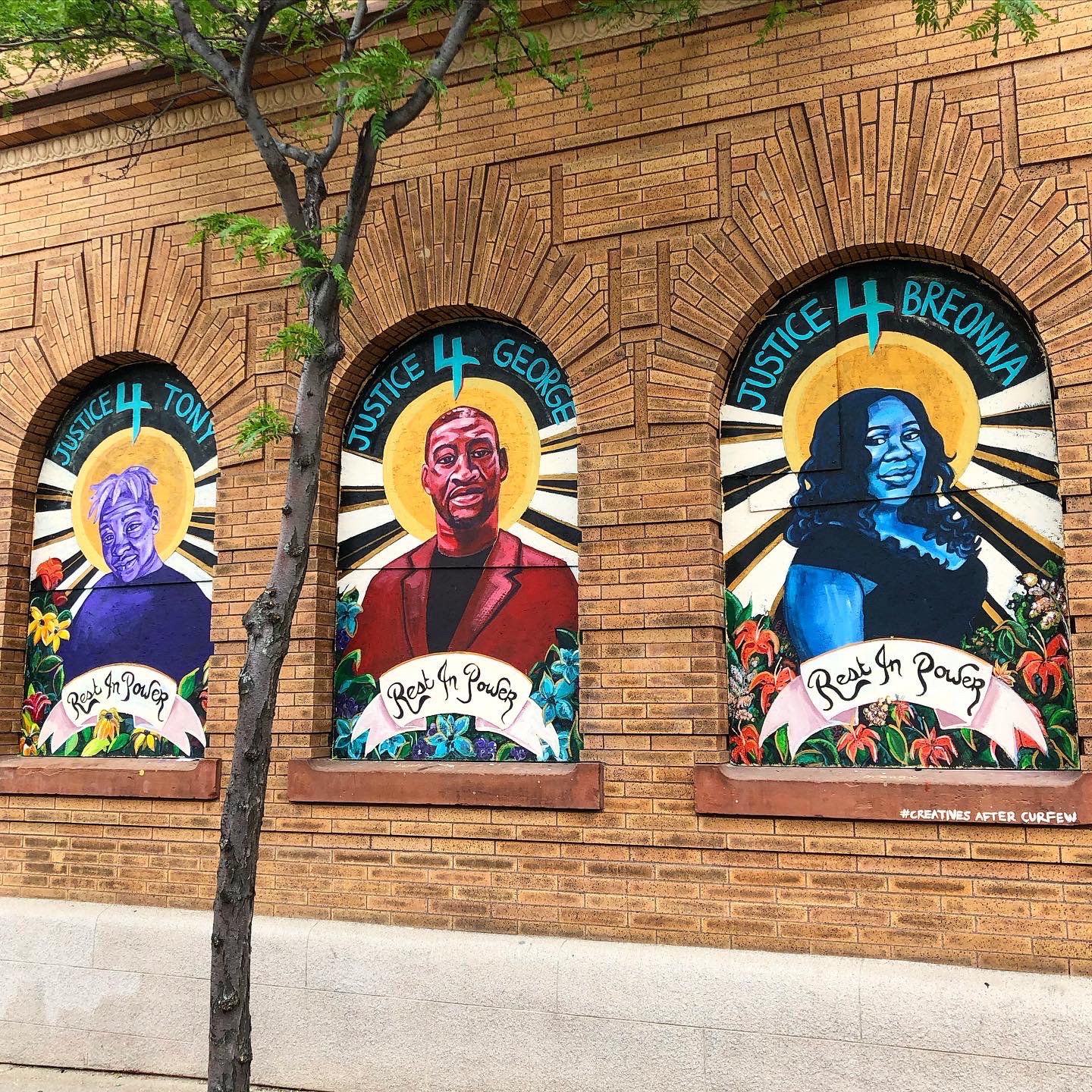 A mural in Minneapolis, Minnesota depicting three Black Americans who were killed by police officers in 2020: George Floyd, Tony McDade, and Breonna Taylor. This mural was painted by Leslie Barlow as part of the Creatives After Curfew program organized by Leslie Barlow, Studio 400, and Public Functionary.