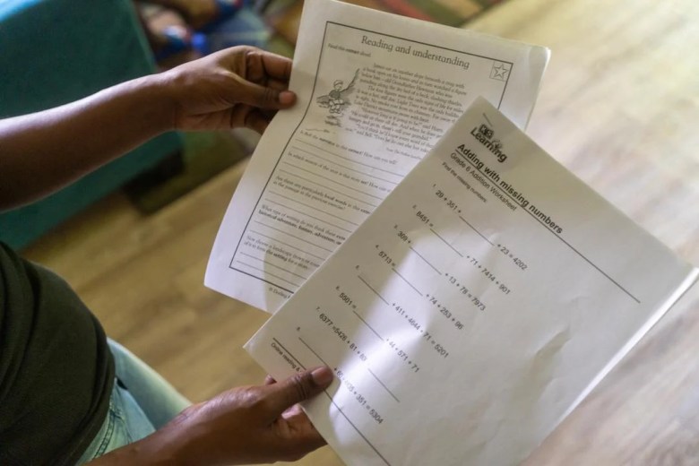 Rosalind Crawford holds two worksheets she printed off for her sons to supplement their education after all five were indefinitely sent home for virtual learning by their school district. 