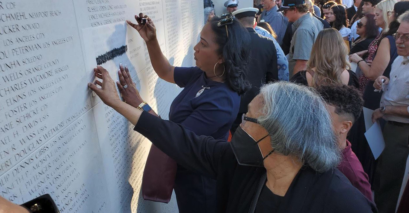 The family of Ronald Yale Wiley visits the California Firefighters Memorial Wall to trace his name engraved on the monument. Wiley, who died in the line of duty in 2007, was a deputy marshal for Richmond’s Fire Department. Photo by Antonio Ray Harvey.