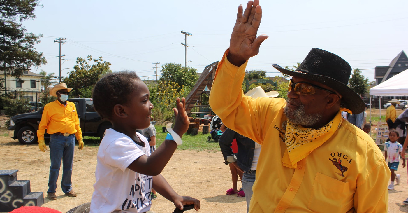 The Oakland Black Cowboys Association will hold an event to teach children the love of riding at Fairyland on Feb. 14. Here, a member of the OBCA high-fives a young rider at an event in 2021. Facebook photo.